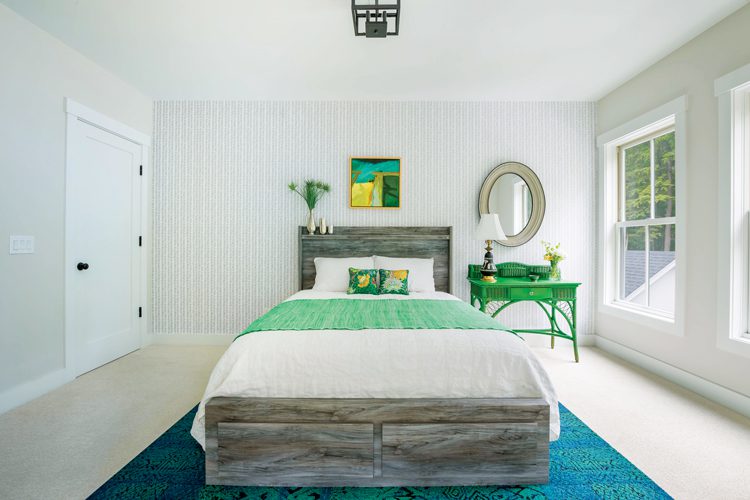 Bright pops of green greet you in the guest room inclue the green throw blanket on the all white bed and evergreen colored mini desk