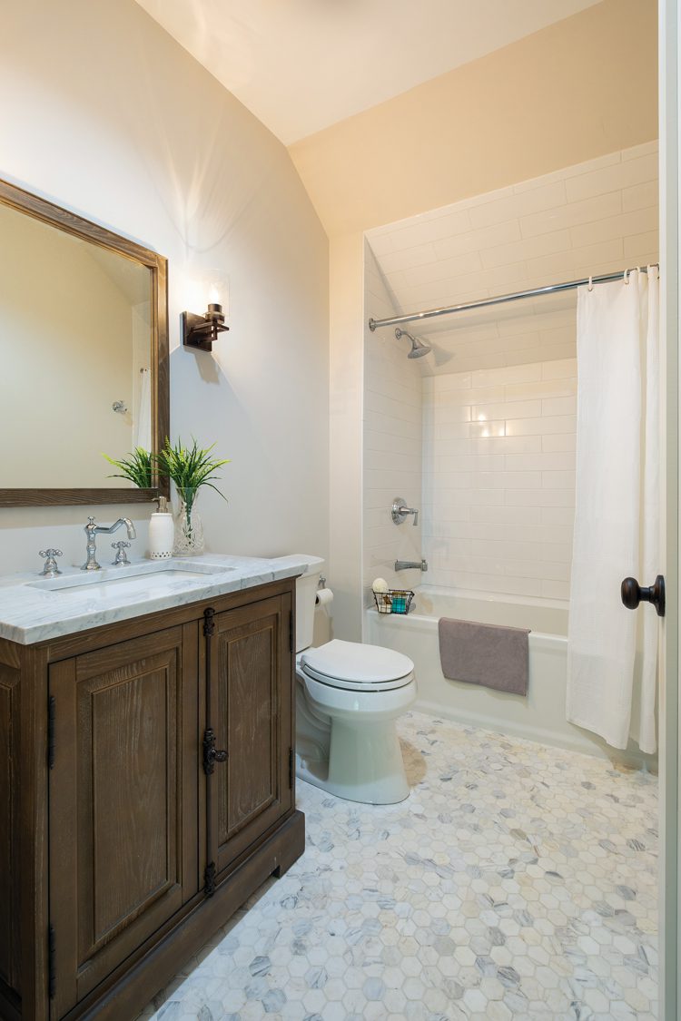 The bathroom has hexagon shaped tile in hues of gray and white