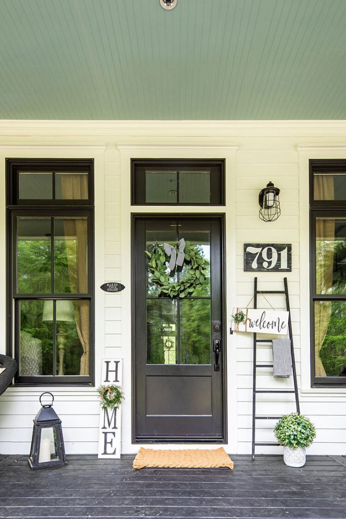 Front covered porch with black door and sign art