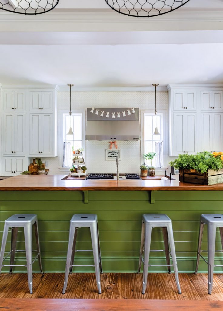Kitchen are a with green island and metal bar stools