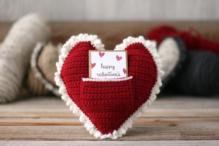 A red heart shaped pillow with a pocket for notes