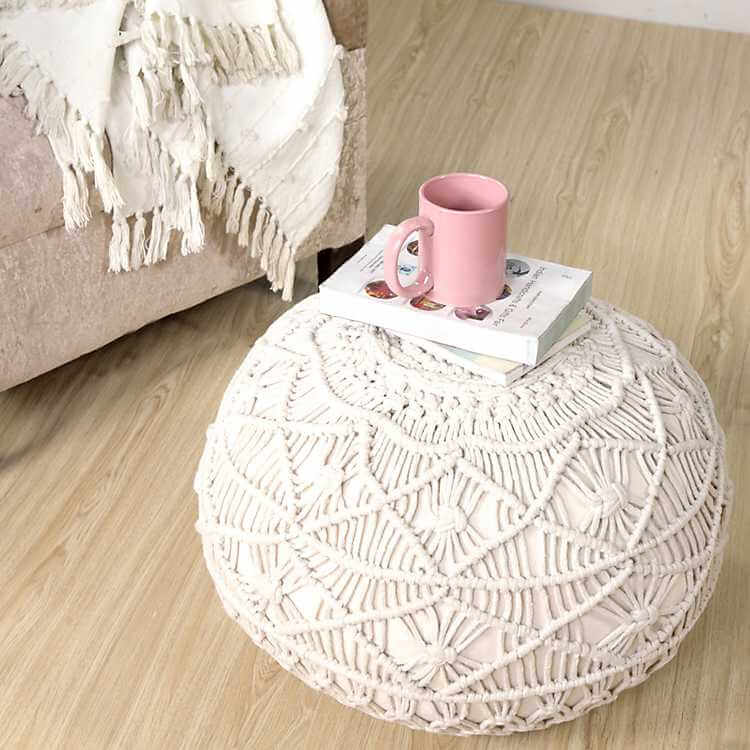 Woven boho farmhouse style pouf on floor with mug on top
