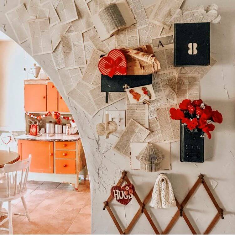 Pages from novels are laid flat on a wall beside other romantic touches like roses and hearts on a farmhouse entryway for Valentine's Day decor