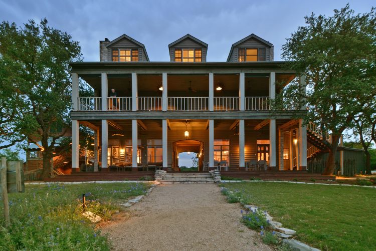 The main building of Sage Hill with large white columns and a large plantation style home deck and porch for spring break destinations