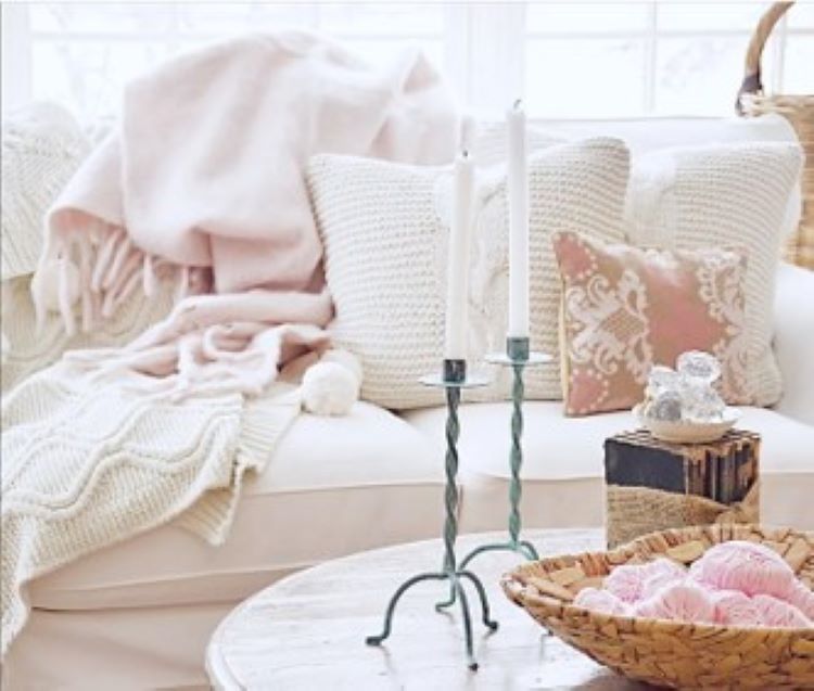 A white couch with soft pink throw pillows work as wonderful valentine's day decor beside a table with a stack of vintage books with a burlap bow