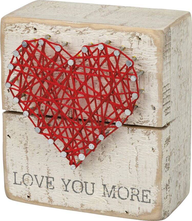 A sign with string art made to shape a heart in red string