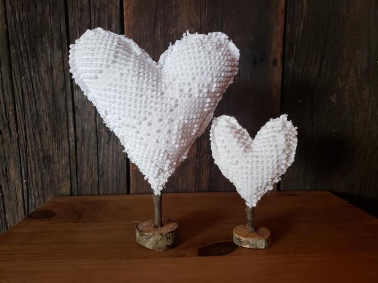 Two stuffed white hearts are standing on wood stands
