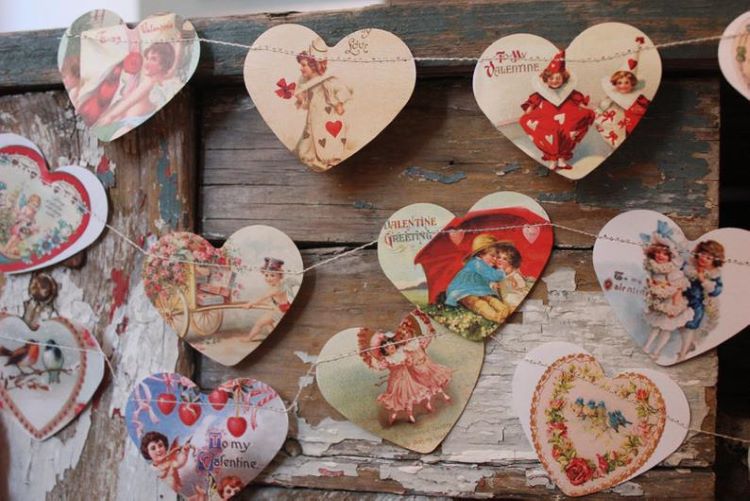 Vintage Valentines cut into hearts and hanging on a string to make a garland