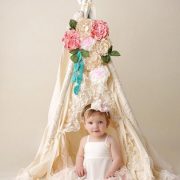 Little girl inside a teepee with flowers and lace