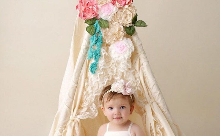 Little girl inside a teepee with flowers and lace