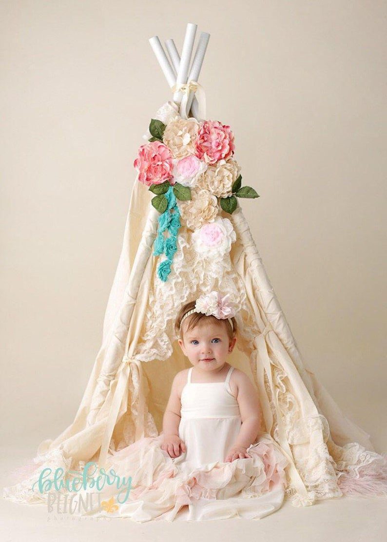 Little girl inside a teepee with flowers and lace