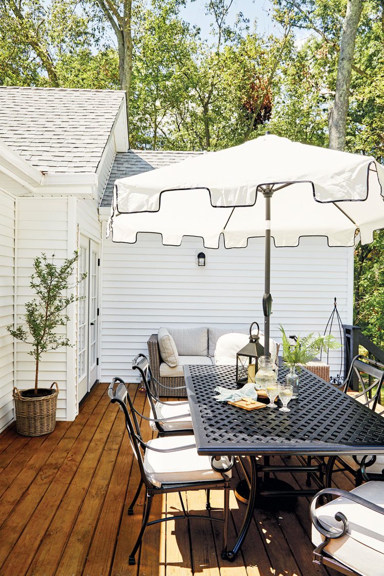 The deck has wood floor and black iron-based furniture. 