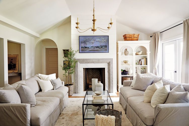 Soft gray sofas with glass coffee tables with a black wire frame. All of the furniture sits on top of an old-fashioned rug.