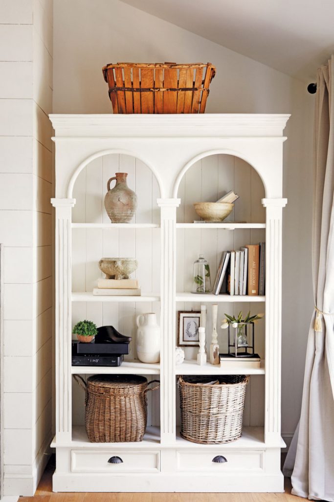 A white bookcase gives a built-in look. The bottom shelves have provincial wicker baskets