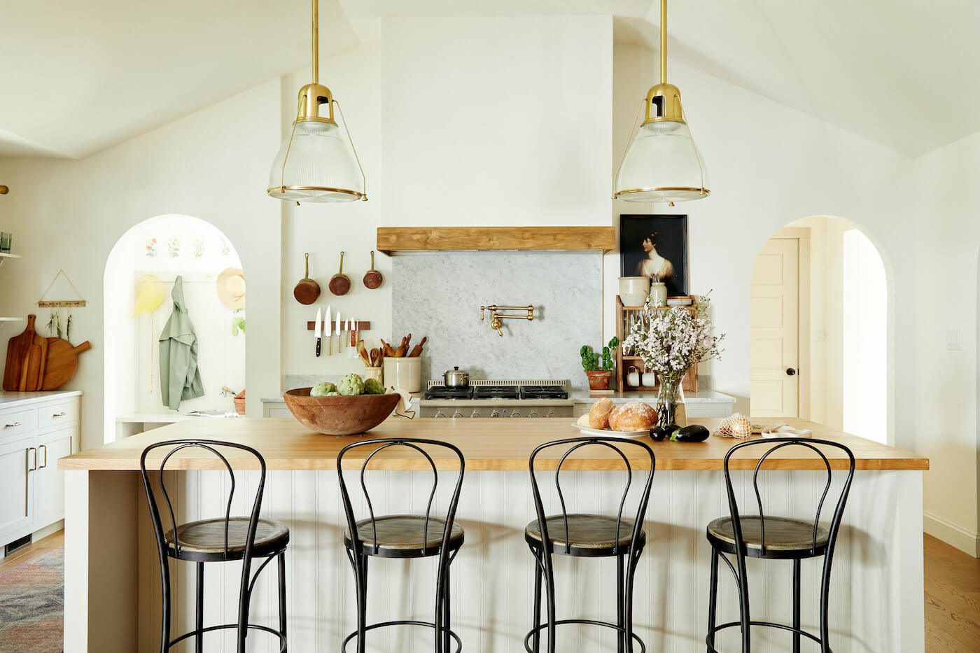 Wood countertops are paired with white cabinets beside large black bar stools