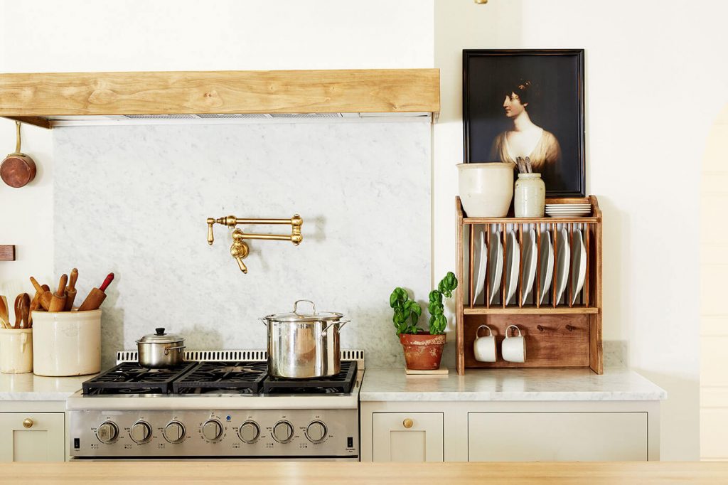 Vintage art hung over a dish rack in the kitchen next to the stove