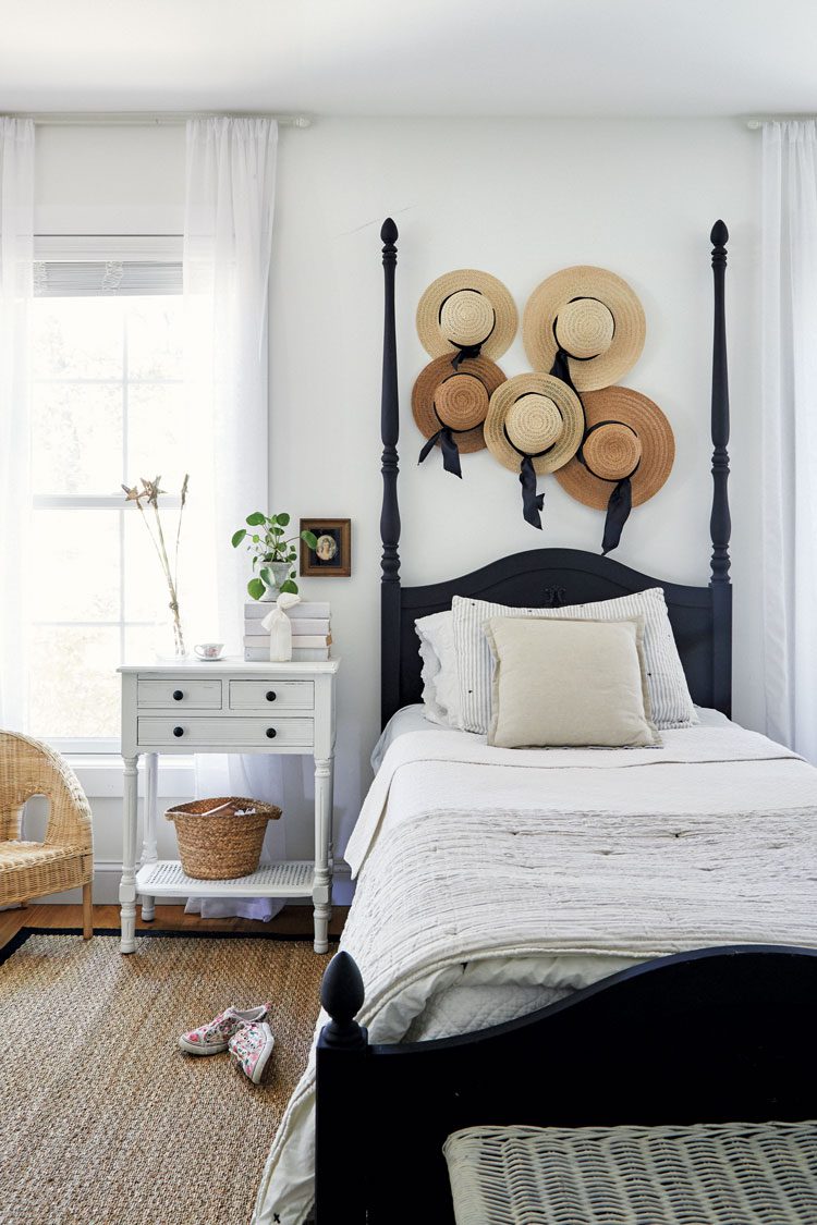 Deb's daughter's room is primarily white and black. Over the headboard is a collection of straw hats with dark ribbons tied around the bases.