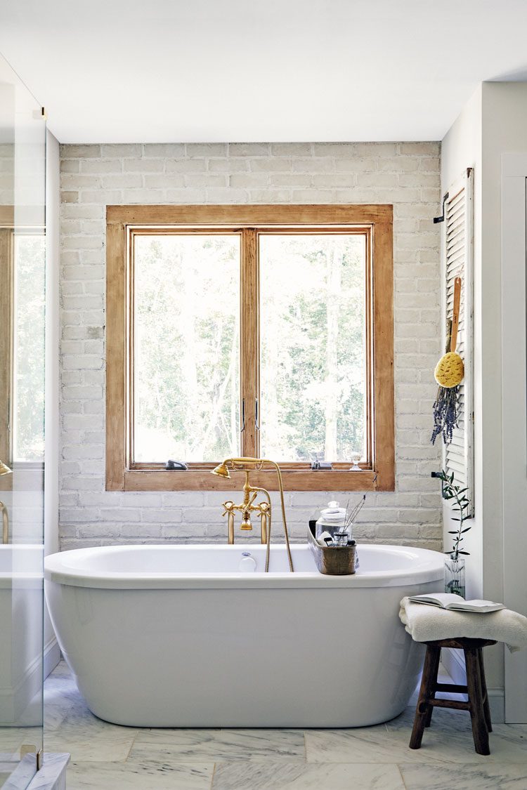 An oversized tub rests below a wood framed window