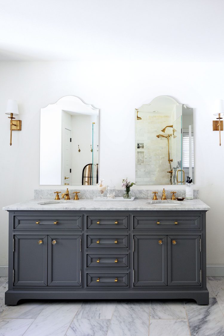 Gray tile pairs well with the mostly white marble counter of this bathroom sink with dusty yellow faucets and knobs