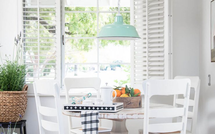 Farmhouse kitchen with white table and chairs and turquoise pendant lighting to refresh a room