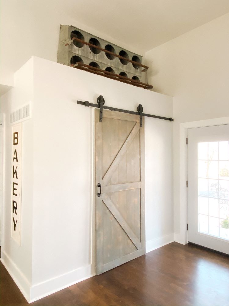 A grey sliding barn door surrounding in white adjacent walls in large family kitchen