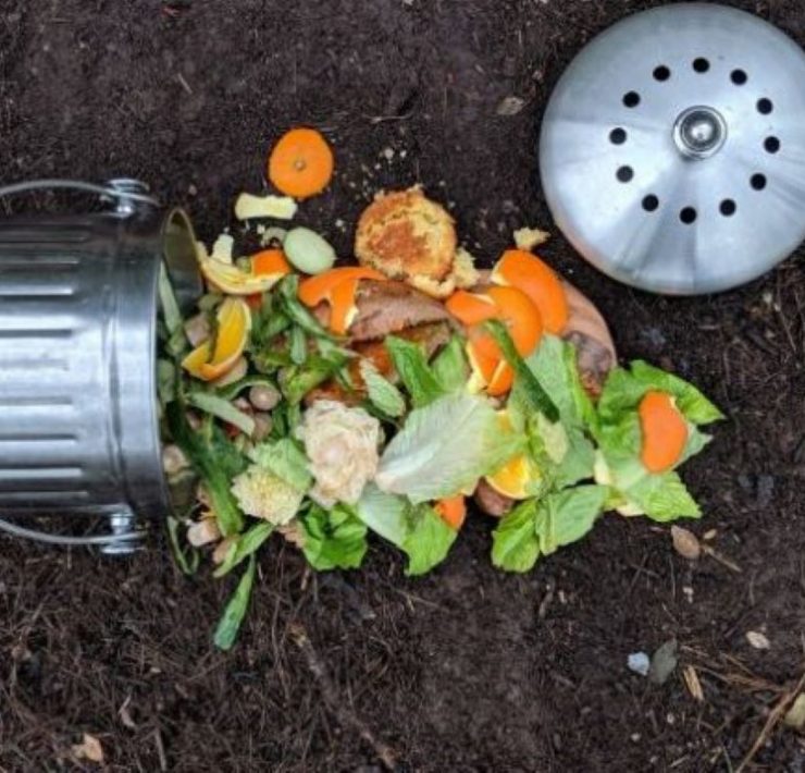 steel compost bin on its side with compost of orange peels and veggies