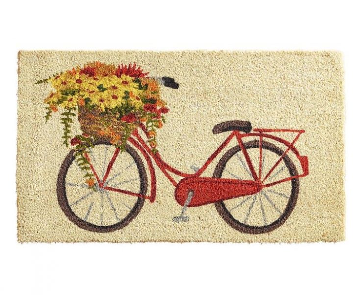 A doormat with a tan background and an image of a red bike with a bike basket full of yellow and orange flowers