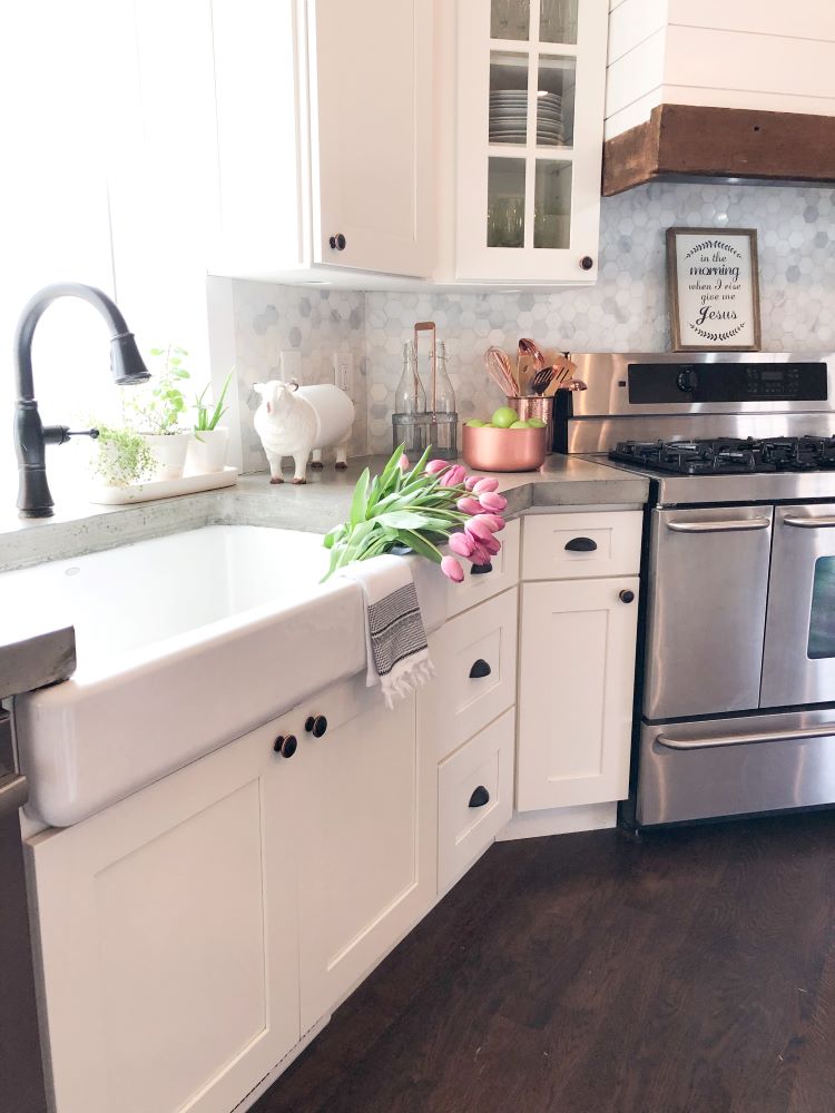 Large farmhouse apron sink over white cabinets and dark hardware in large family kitchen