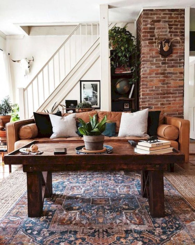 leather sofa in a carmel color leather with white and black throw pillows in front of a rustic wood coffee table
