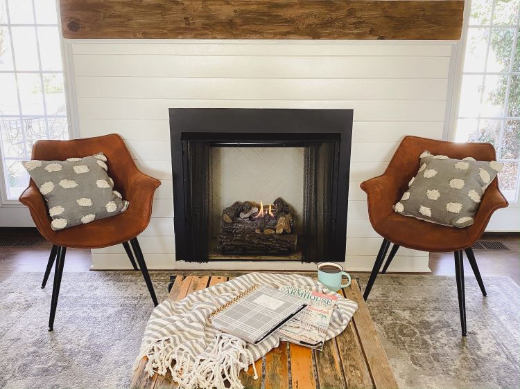 Two identication chairs with grey throw pillows beside a white shiplap fireplace