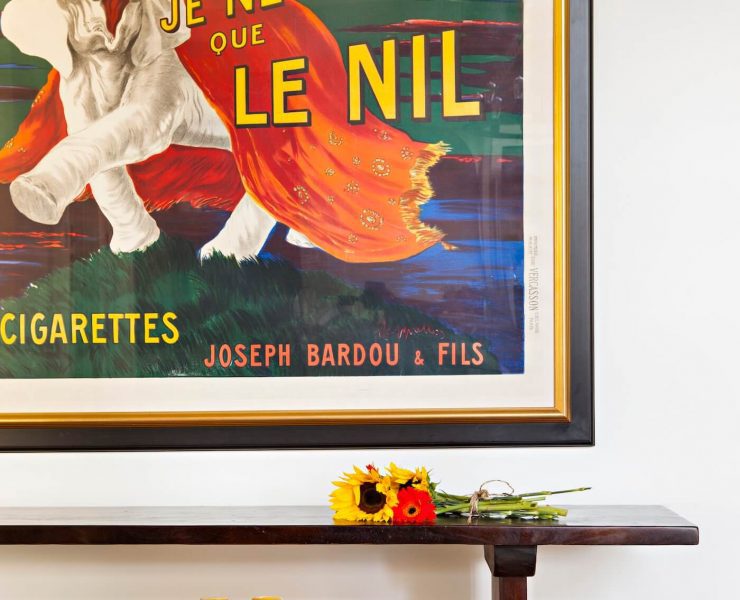 vintage poster on wall in front of bench with sunflowers