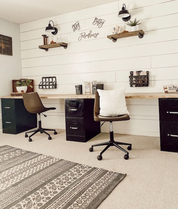 The office wall above the his and her office desk has the words, “itty bitty farmhouse.” The wall is made of white shiplap