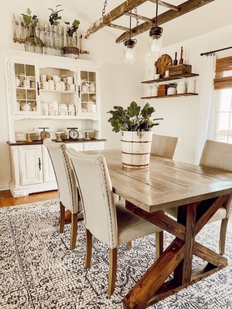 A view of the dining room table showing the gorgeous white china hutch which has a mini white fence placed on top of it.