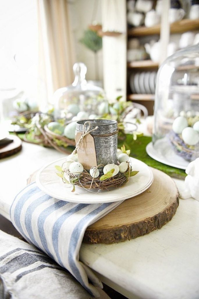 a tablescape with wood slice table settings covered in dainty egg wreathes and tin cups