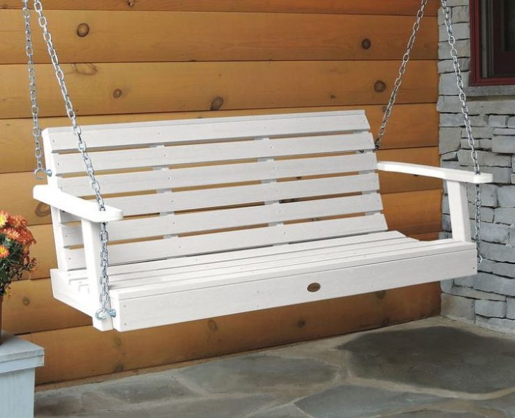 A white porch swing hangs from metal chain