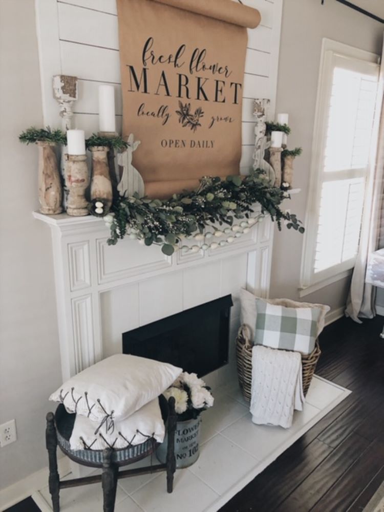 a farmhouse mantel with white shiplap and a layer of eucalyptus and a large unfurled scroll reading “market”