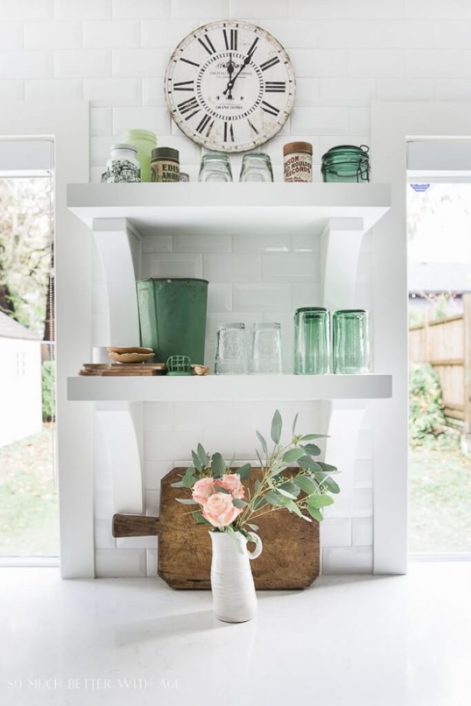 Open farmhouse kitchen shelves covered in green glass cups