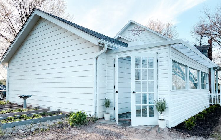 Outside of white barn with greenhouse garden extension