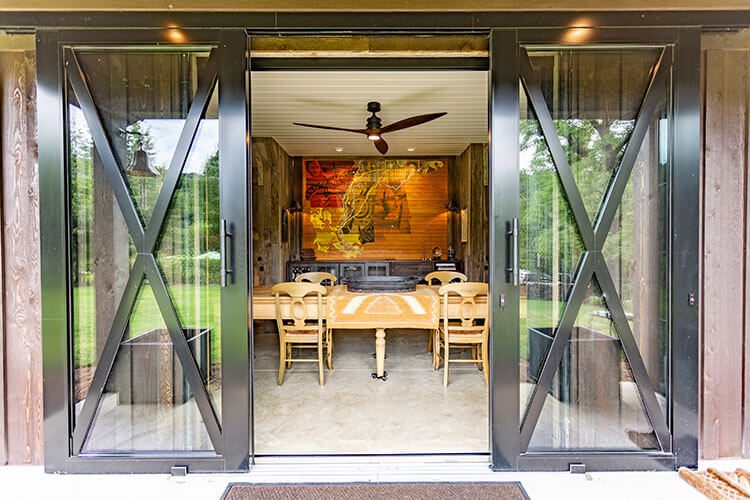 Sliding glass doors leading to a large dining table in the music barn