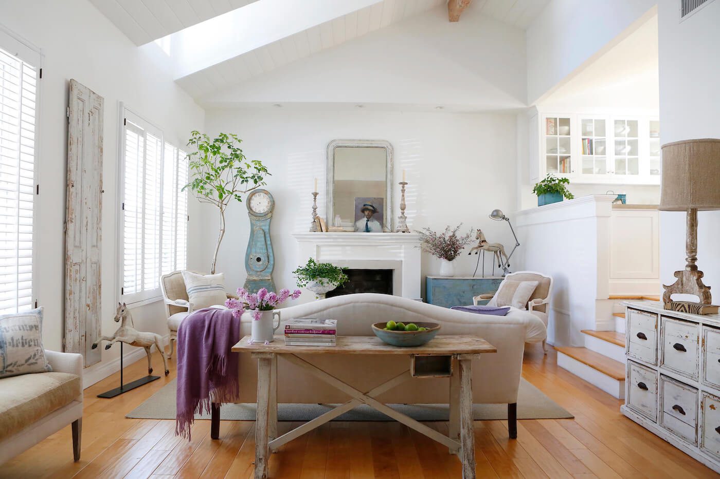 White living room with neutral furniture, purple blanket and vintage finds