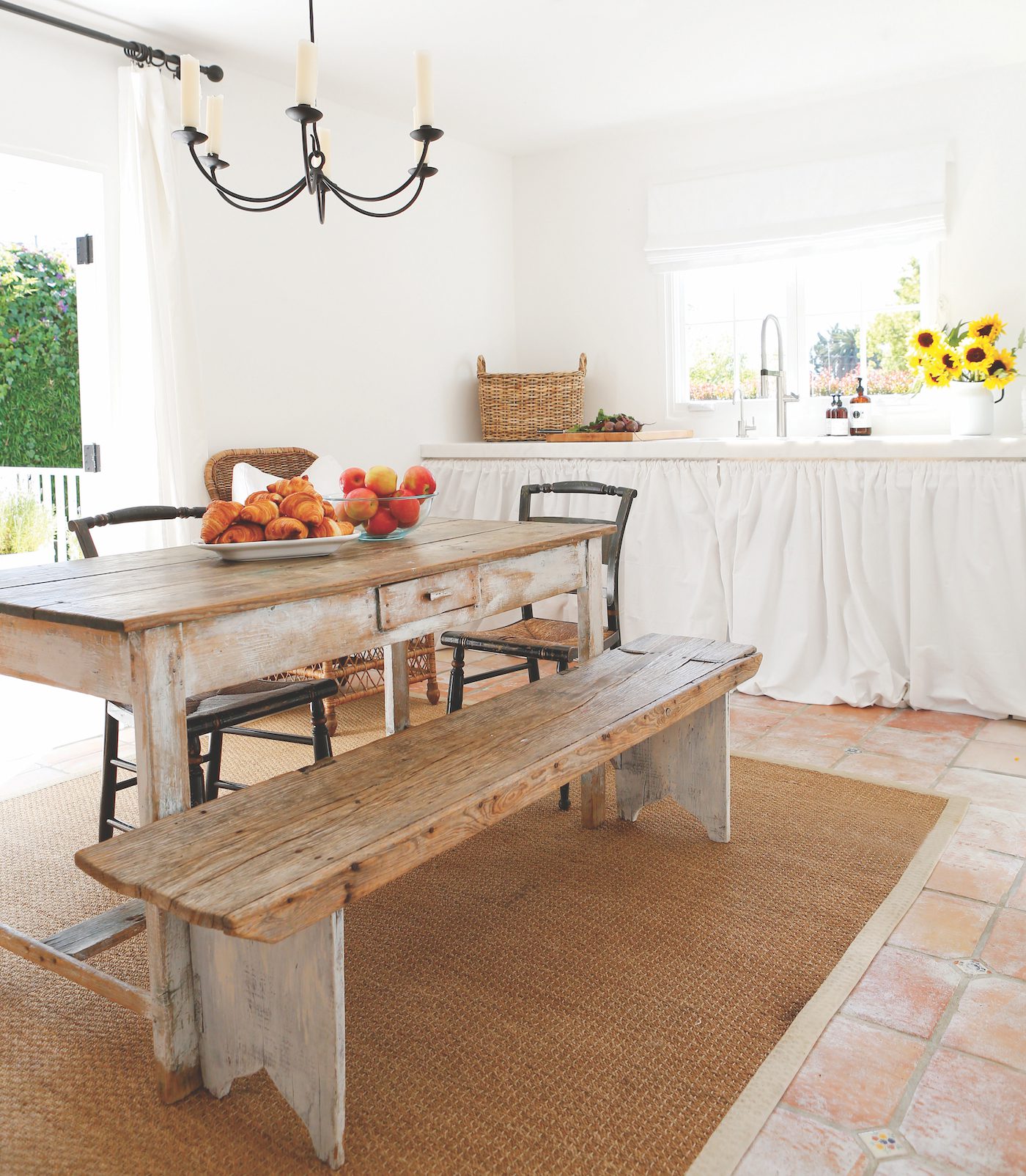 White open farmhouse kitchen with rustic wood table and sunflowers