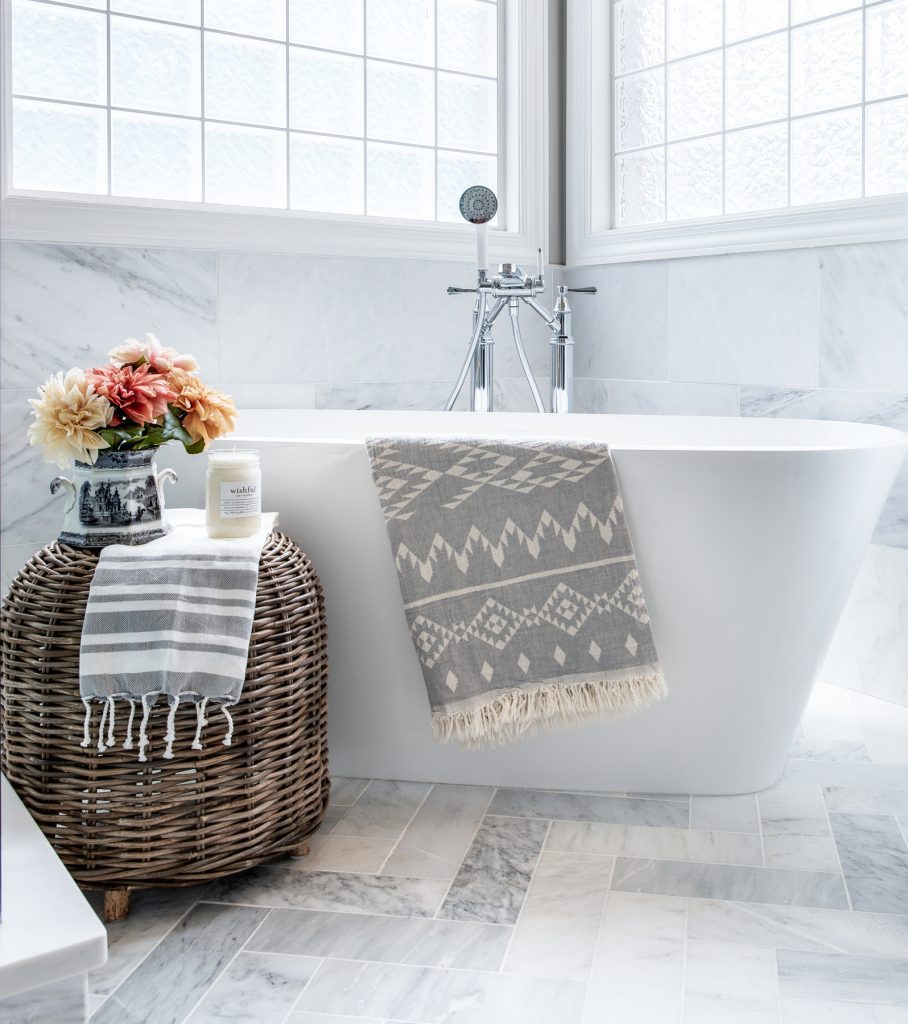 Freestanding bathtub in bathroom with windows and marble flooring