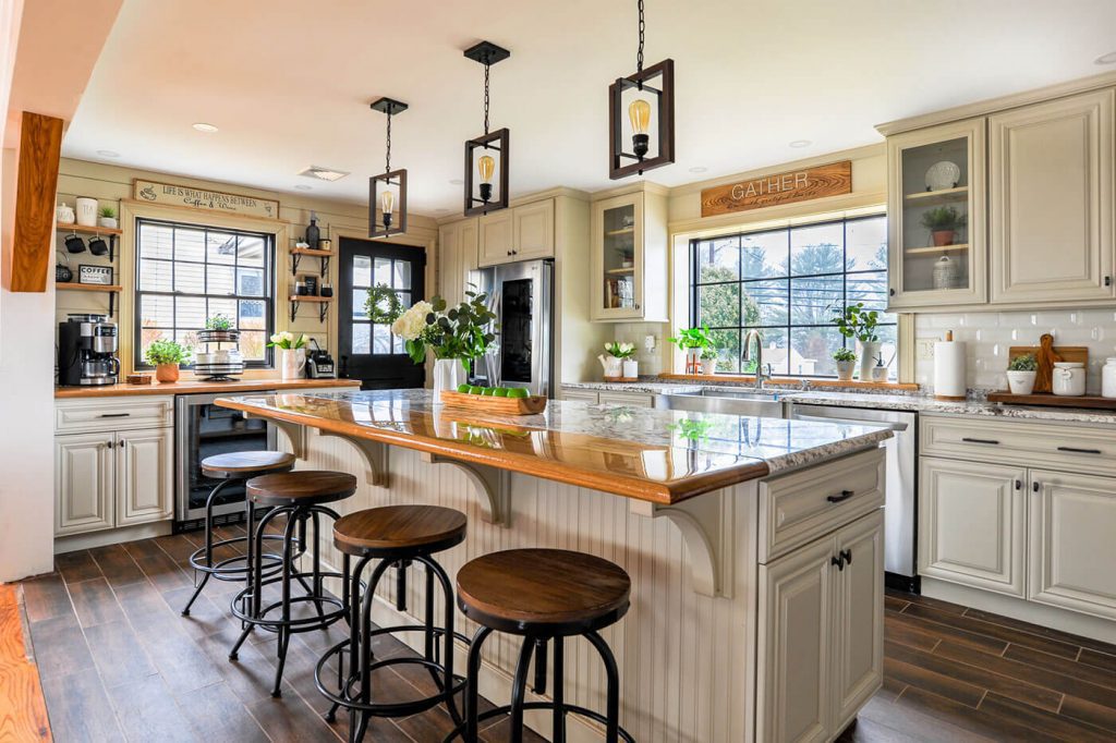 Open kitchen with island and bar stools, white cabinets and hanging pendant lights