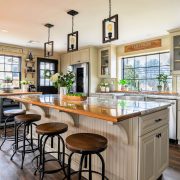 Open kitchen with island and bar stools, white cabinets and hanging pendant lights