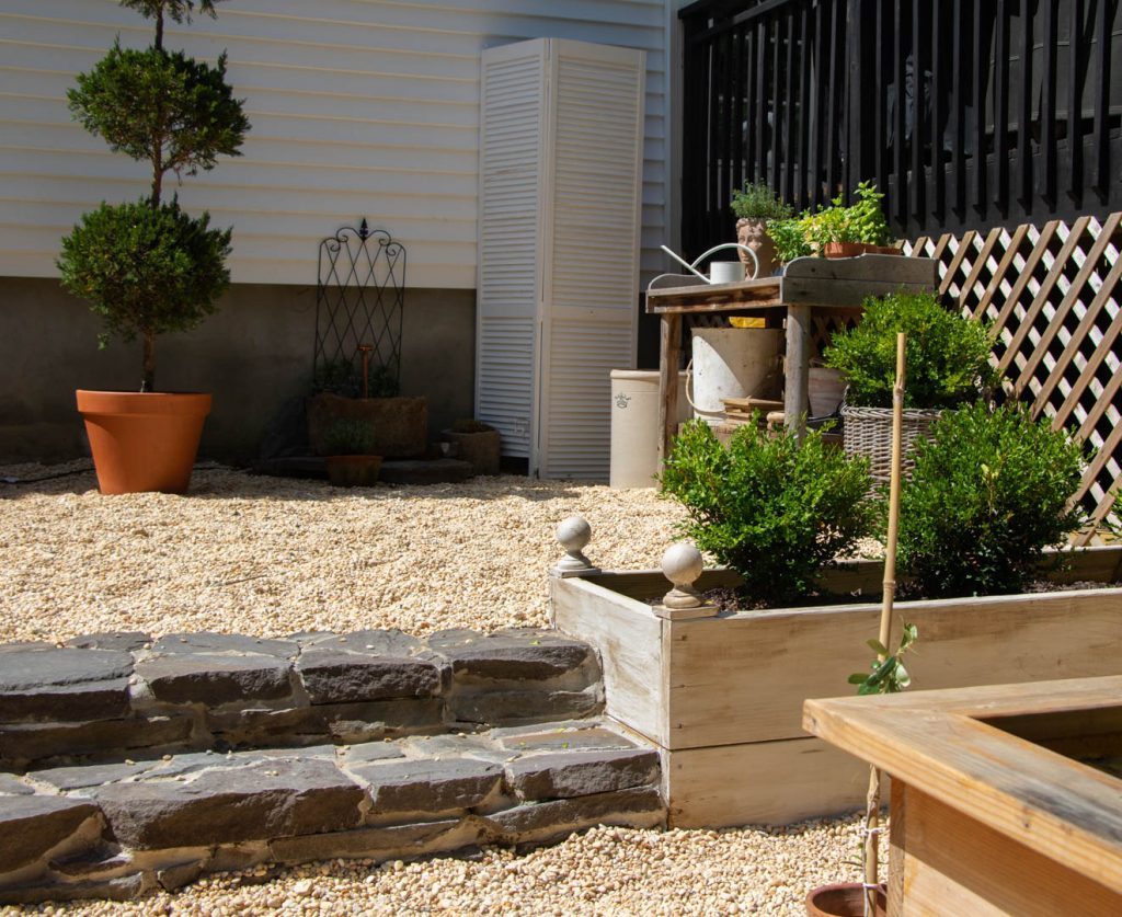 Pea gravel walkway with raised beds and boxwood plants