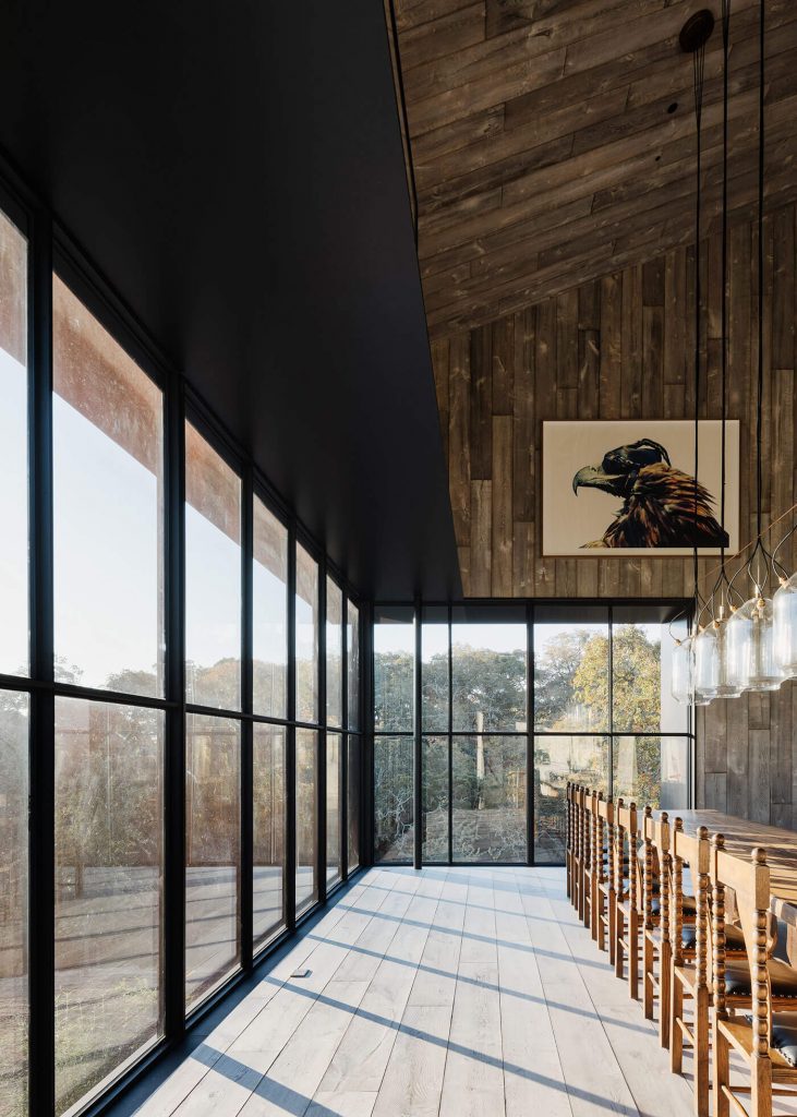 Dining room in modern barn home with wall to wall windows and wood paneling