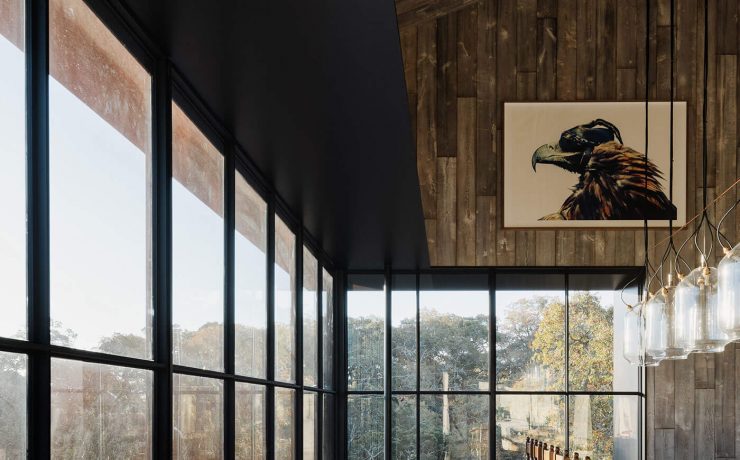 Dining room in modern barn home with wall to wall windows and wood paneling