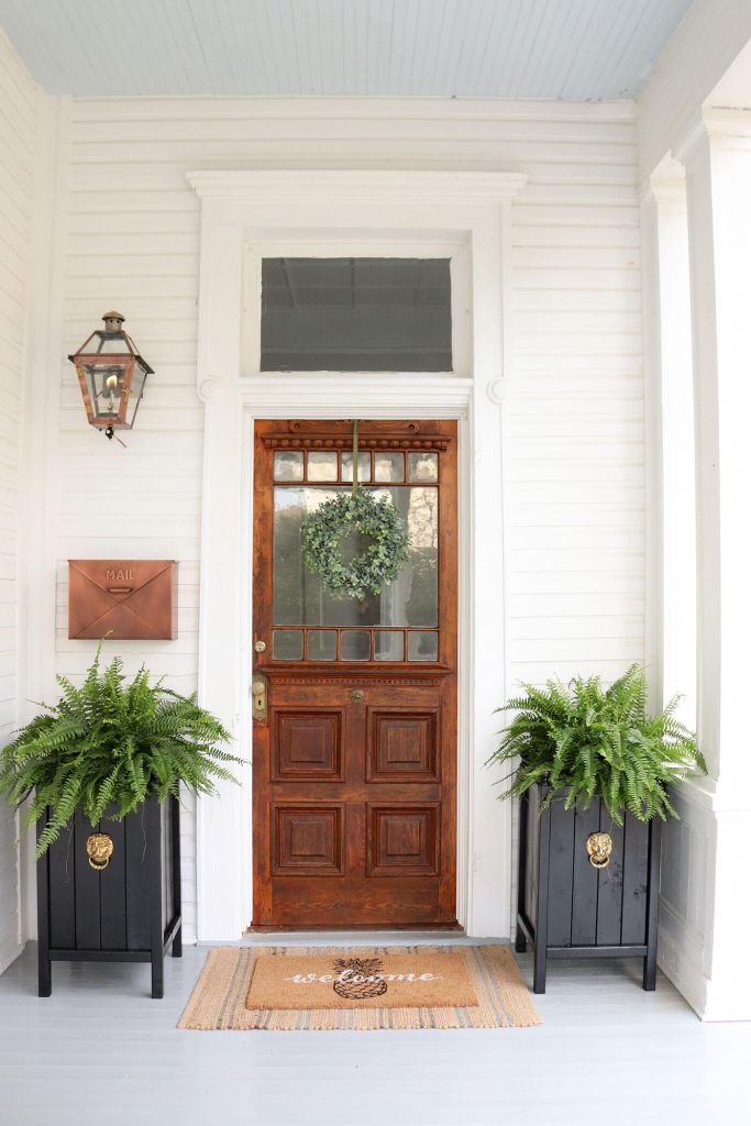 Front door on porch with plants on either side
