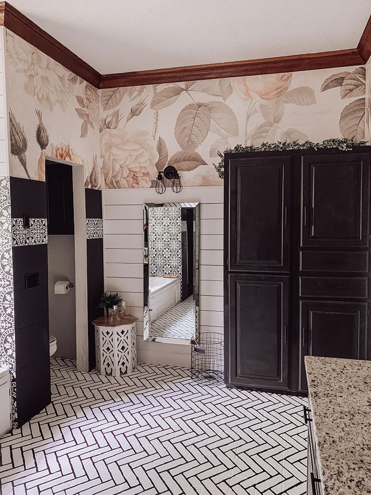 White tile and black cabinets with floral wallpaper in bathroom
