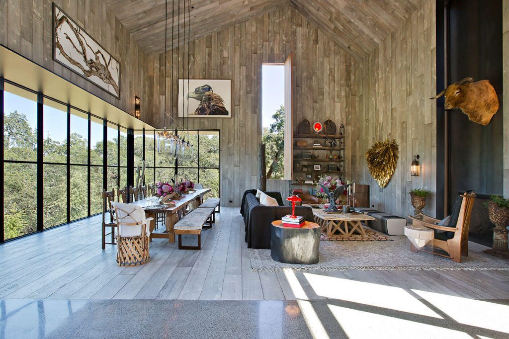 Dining and living room with rustic wood paneling, sofa and lots of windows